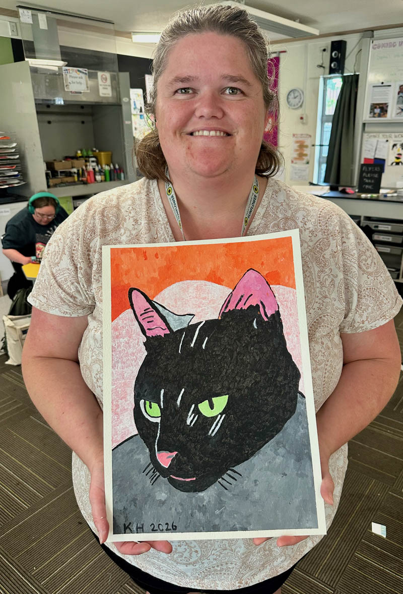 Kayla Hood holds a painting of a black cat with green eyes